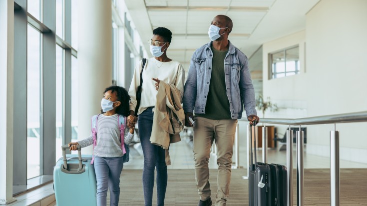 Tourist family walking through passageway in airport.