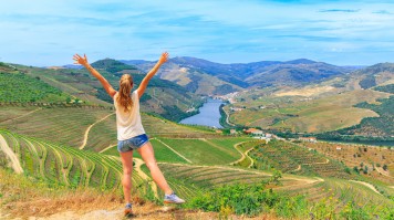 A woman on a hike in the vineyards of Douro Valley, with the Douro river visible in the background