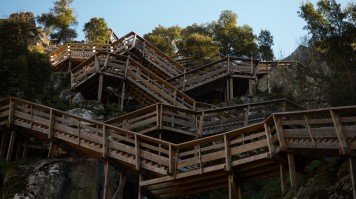 wooden stairs snaking up a rocky cliff.