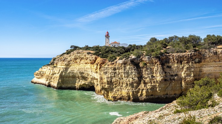 The Alfanzina lighthouse visible during a hike in one of Algarve's coastal trails in Portugal 