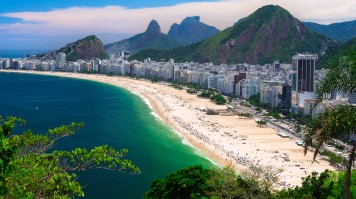 The Copacabana beach with buildings and mountains in the back. 