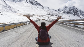 A traveler sitting on the road and enjoying the view on his trip to Arakoram Highway.