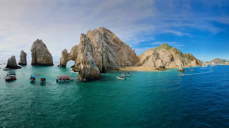 Tourist-packed boats seen on the rocky coastline of Cabo San Lucas, Mexico