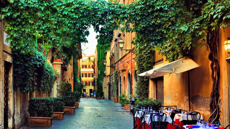 Beautiful ancient street in Rome lined with leafy vines and cafe tables, It