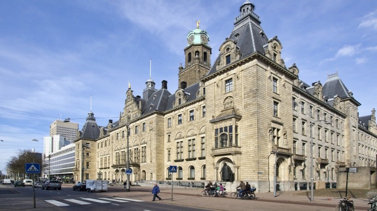 View of city hall in Rotterdam with people and traffic.