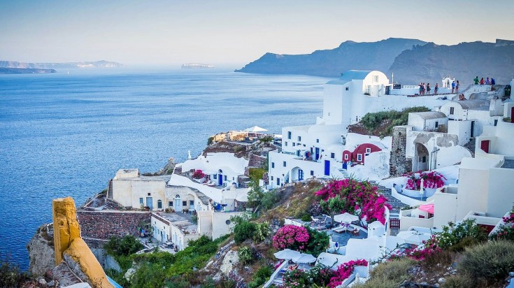 A sea-side view of Santorini with clear blue water and white painted houses. 