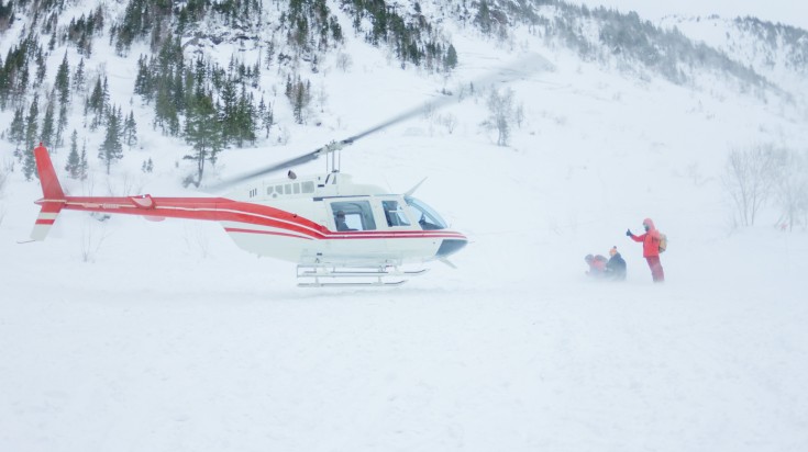 Skiers dropped off at a ski spot by a helicopter.