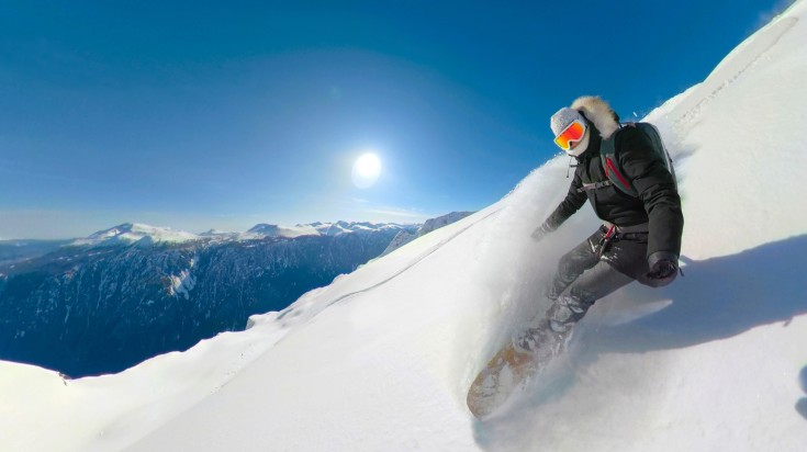 A woman snowboarding in the snowy mountains in Canada in January.