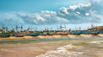 Relax on a beach in Hikkaduwa and learn how to surf Row of fishing boat on Sri Lanka beach