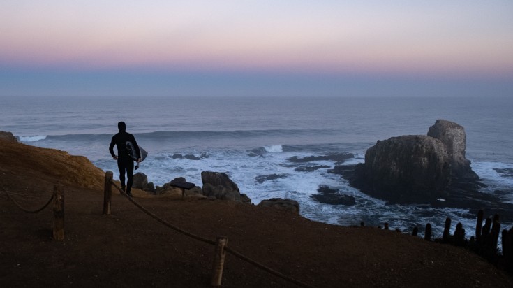 Surfer walking towards Pichilemu to surf—one of the things to do in Chile.