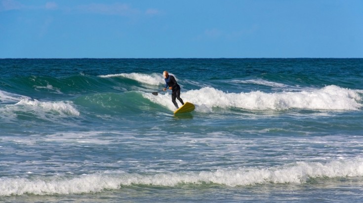 A man surfing through the waves of the sea in Israel during December.