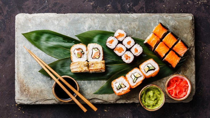 Sushi is prepared with rice and various toppings like salmon and veggies.