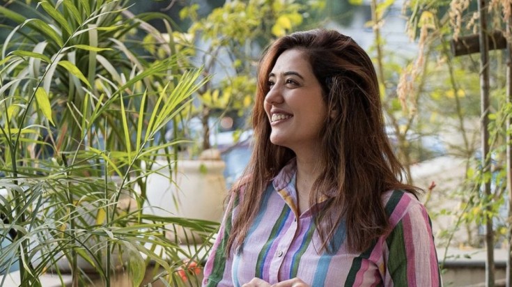 Tanya Khanijow showcasing her vibrant style against a green backdrop.
