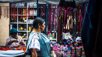 People in traditional clothes shopping at a market in Otavalo