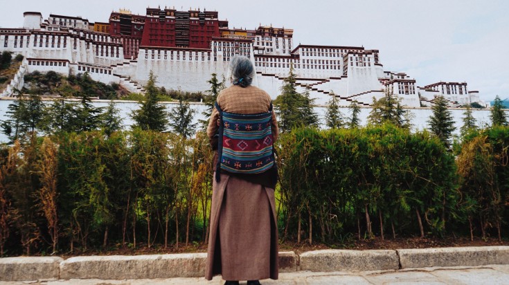 Potala Palace is one of the biggest attractions on a trip to Tibet. An old Tibetan lady gazes at the Potala Palace