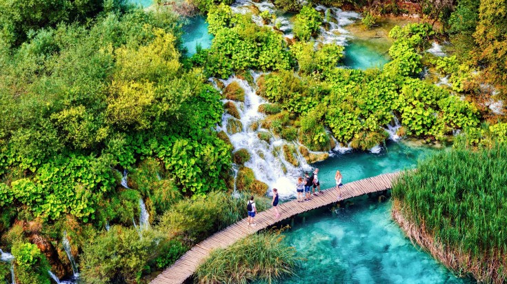 Tourists hiking the waterfalls path in Plitvice Lakes National Park.