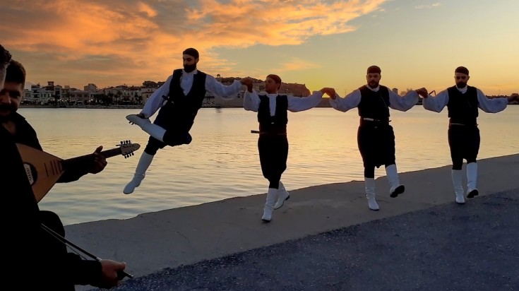 Men dancing traditional dance Rethymno with setting sun on background.,