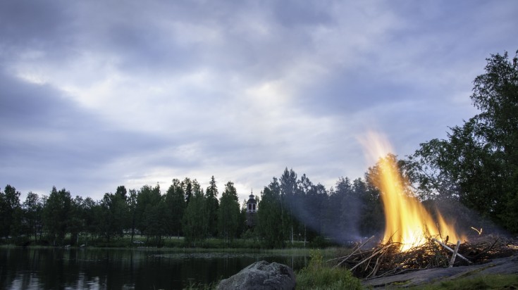 Traditional midsummer bonfire near a waterbody in Savonlinna.