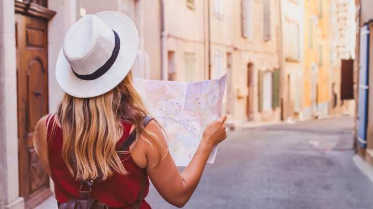 A traveler girl is looking at map on the street to get directions.