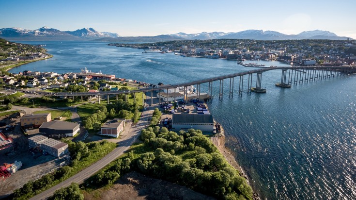 Aerial view of the striking Tromso Bridge surrounded by serene blue water.