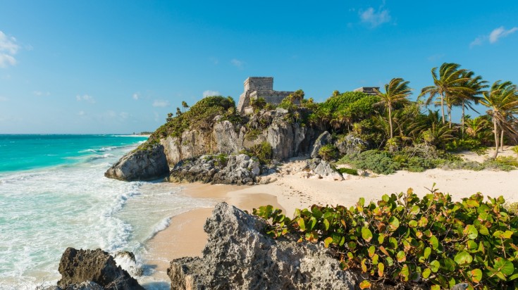 Mexico's Tulum beach with trees, hills and water. 