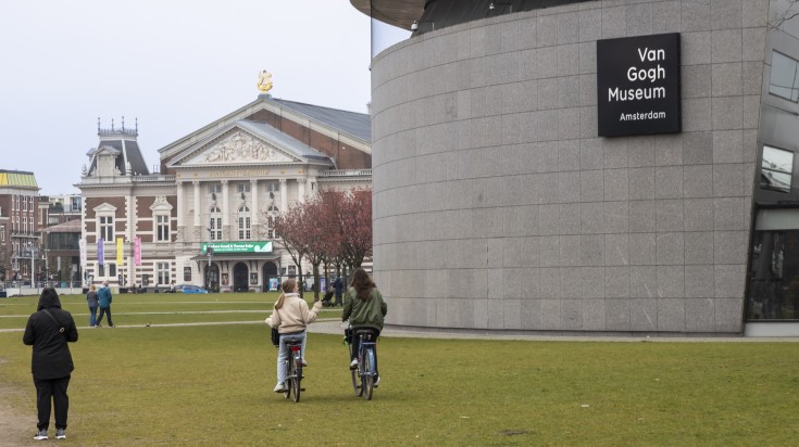 People cycling and walking around Van Gogh Museum on a winter day.