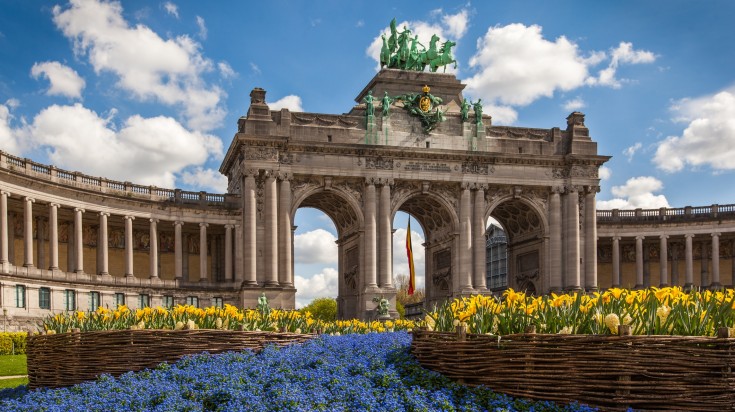 Visit Belgium in March to witness the Triumphal Arch amidst spring blooms.