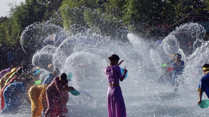 Locals splashing water at each other on a sunny day.