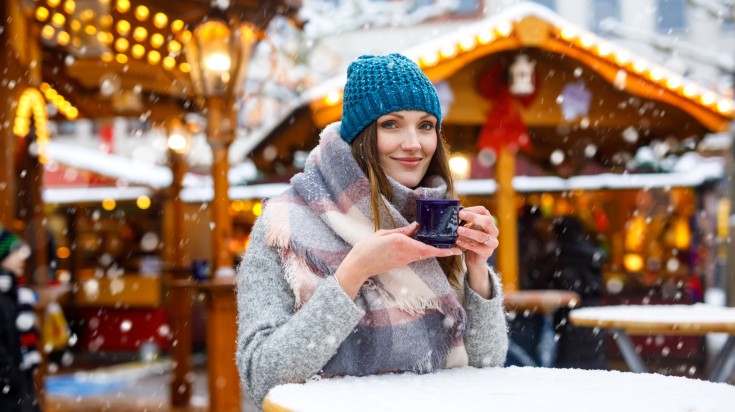 A girl enjoying warm drink in the Christmas market in Germany during Novemb