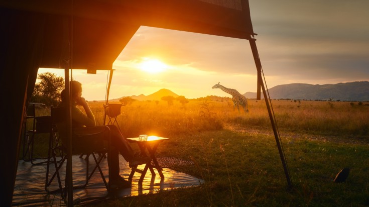 Woman rests after safari in luxury tent during sunset camping in Tanzania i