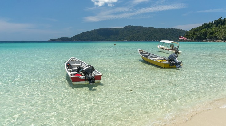 Boats on clear water at Perhentian Island in Malaysia in July.