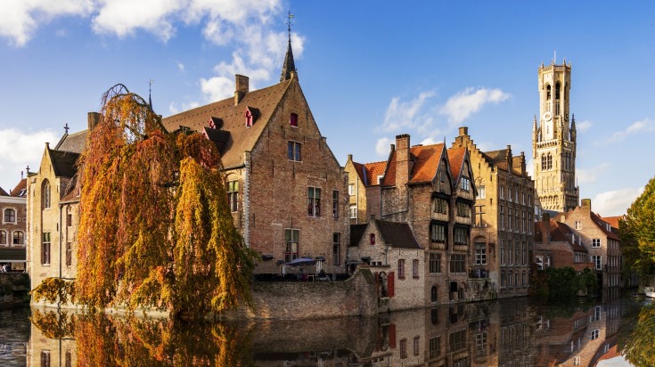 Canals and buildings of Bruges with fall foliage in Belgium in September.