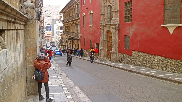 Traveler taking photos of red-colored vintage colonial building.