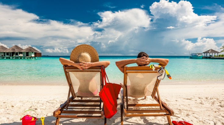Couple in loungers on a tropical beach in the Maldives in October.