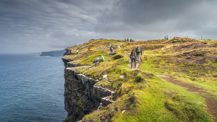 Group of people or tourists hiking the iconic Cliffs of Moher.