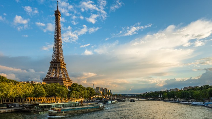 the Eiffel tower stands next to a river in Paris