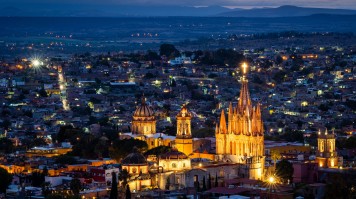 A well lit cathedral and the town at dusk in Mexico