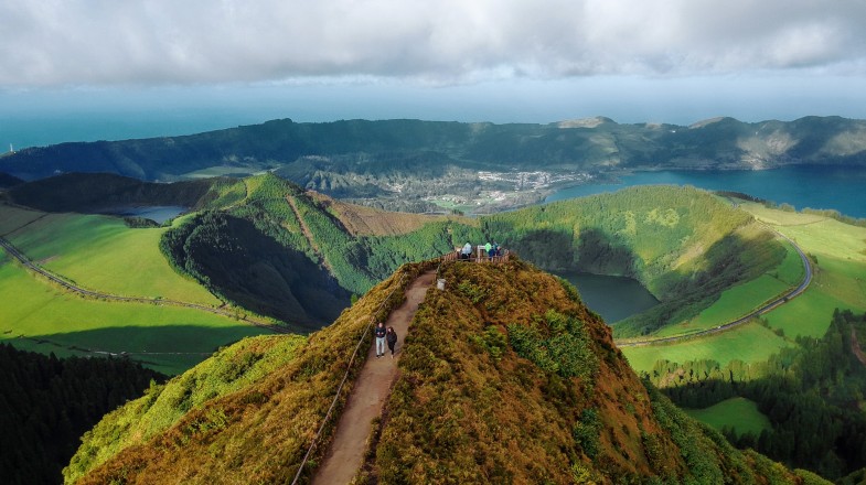 People on a trail to a viewpoint on top of hill with twin lakes and sea