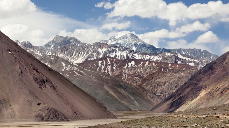 Snow-capped peaks that run down into rugged cliffs form the dramatic backdrop of Cajon del Maipo.