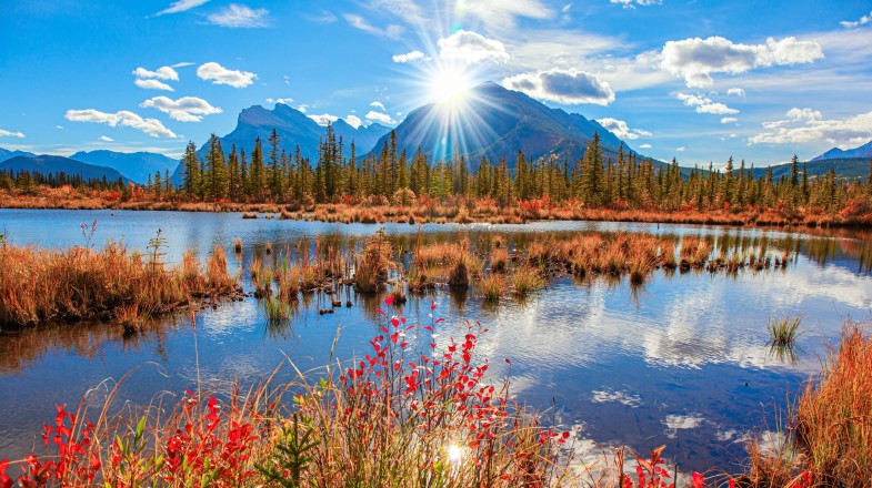 Autumn foliage with Rocky Mountain in the background and the Lake Vermilion reflecting the clouds in Canada in October.