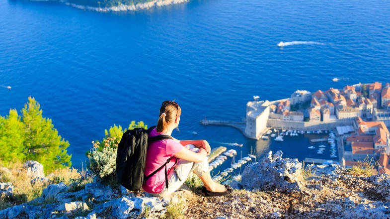 A tourist hiker at the top of the mountain admiring the view during summer.