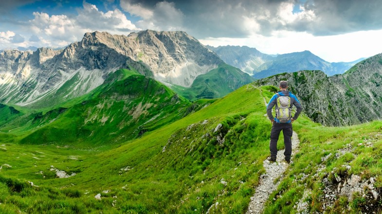 Take in the breathtaking panoramic views of the Bavarian mountains as you hike through the picturesque trail in Germany in June. A hiker man on hiking trail at Bavaria in Germany in June.