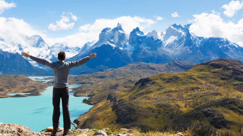 A hiker with open arms in Torres del Paine National Park during his hiking in Patagonia.