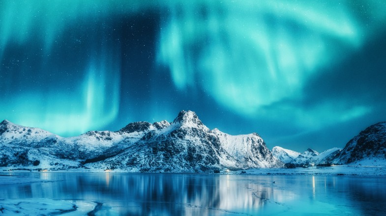 Aurora borealis above snowy mountains in Iceland in February.