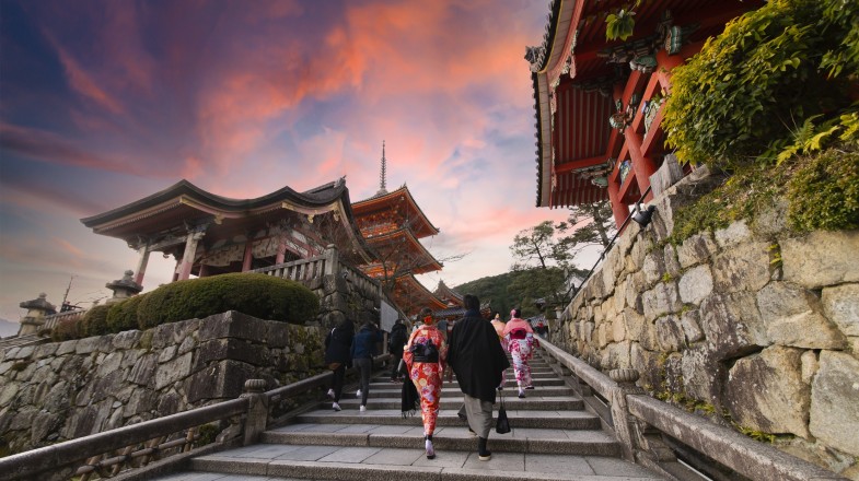 Tourists explore Kyoto under a red sky on a Japan guided tour.