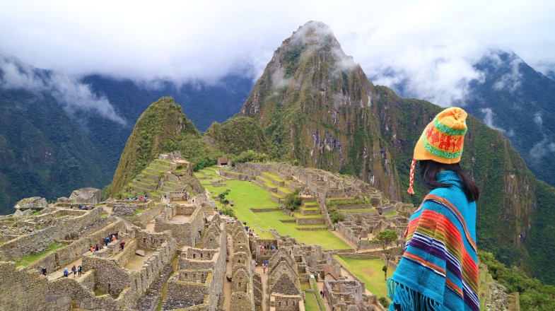 Woman in Poncho and Andean Hat at the ancient Inca Citadel of Machu Picchu, one of the best places to visit in October.