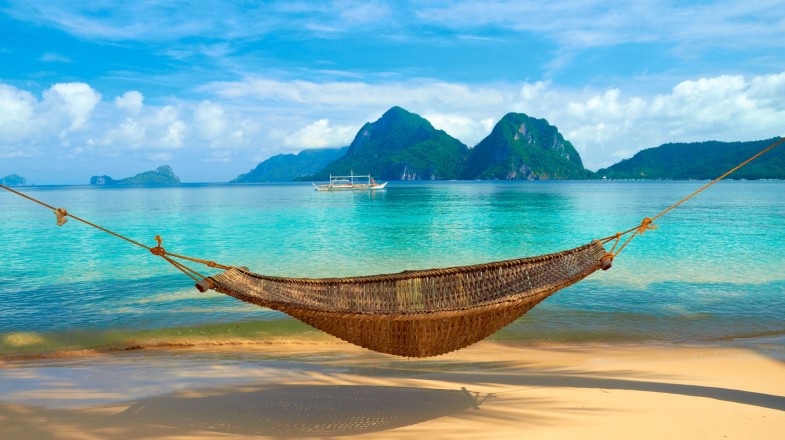 A hammock at the beach with Bacuit Archipelago islands in the distance in the Philippines in January.