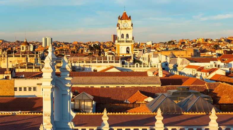 Cityscape of Sucre, one of the best places to visit in Bolivia, at sunset with its colonial style rooftops and Cathedral tower.