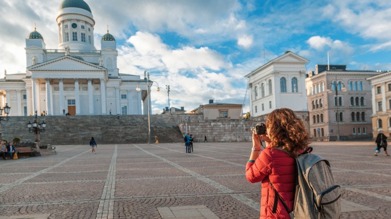 A woman traveler with a camera on Senate Square in Helsinki, one of the best places to visit in Finland on a clear day.
