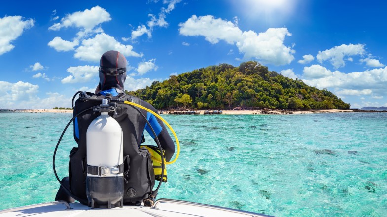 Discover the depths of adventure in crystal-clear waters with scuba diving, just one of the many thrilling things to do in Thailand that promises unforget A man ready to scuba dive, one of the top things to do in Thailand, in Krabi on a sunny day.